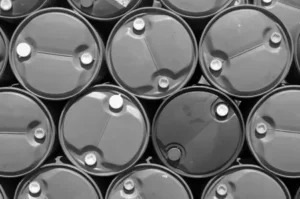 A stack of large industrial metal barrels arranged horizontally in black and white. for hazardous waste containment
